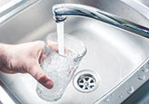 Filling a glass of water at the kitchen sink.